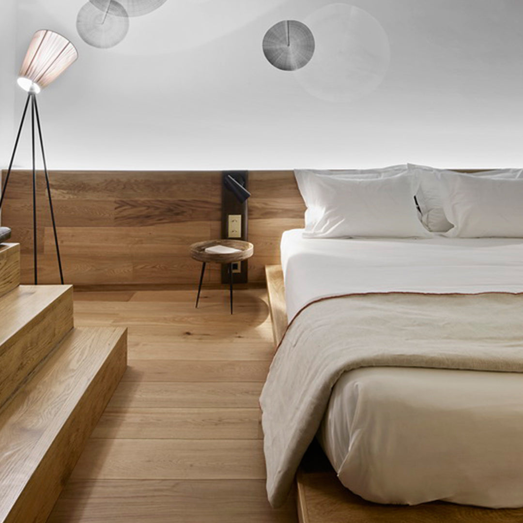 Natural wood tones, soft white bedding, and subtle gray circular patterns create a calming, modern bedroom ambiance.