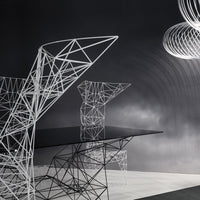 "Modern black table with intricate white geometric wire frame design against a dark background, featuring unique patterns."