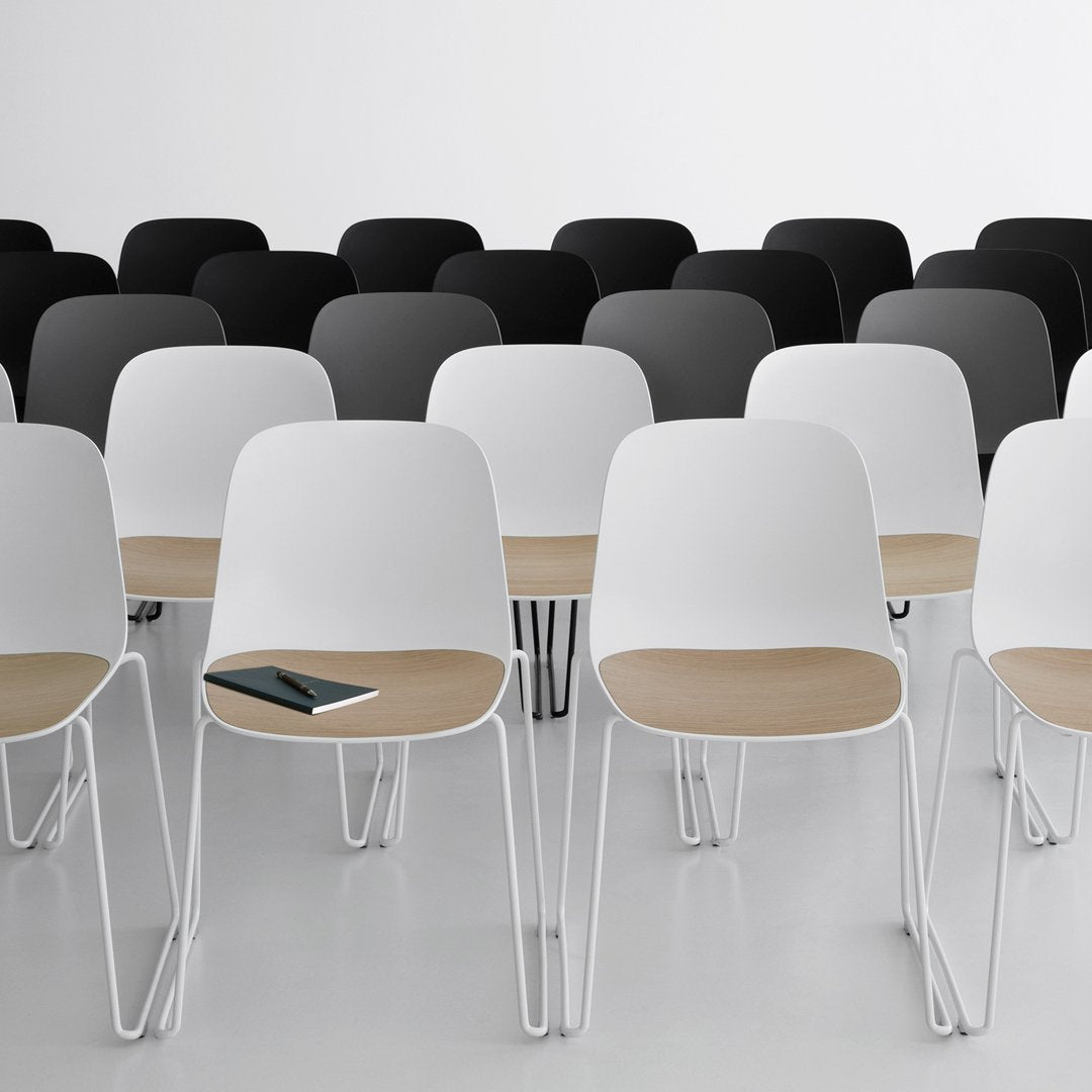 Modern chairs in white and black, featuring sleek, minimalist designs with wooden accents in a stylish arrangement.