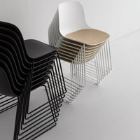Stacked chairs featuring sleek black and white finishes with a wooden seat, set against a minimalist backdrop.