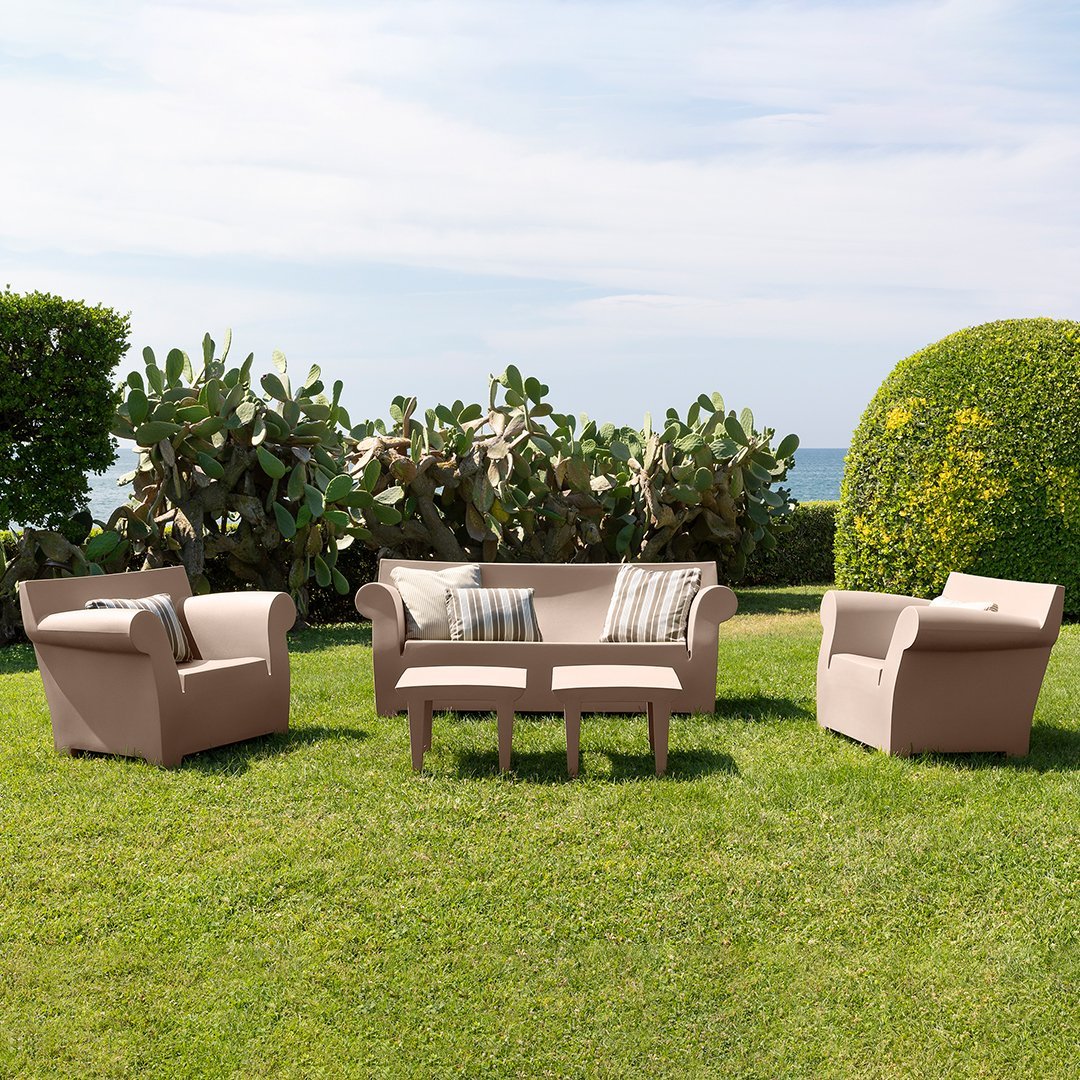 Beige outdoor seating set with striped accent cushions, featuring geometric patterns, on a lush green lawn.