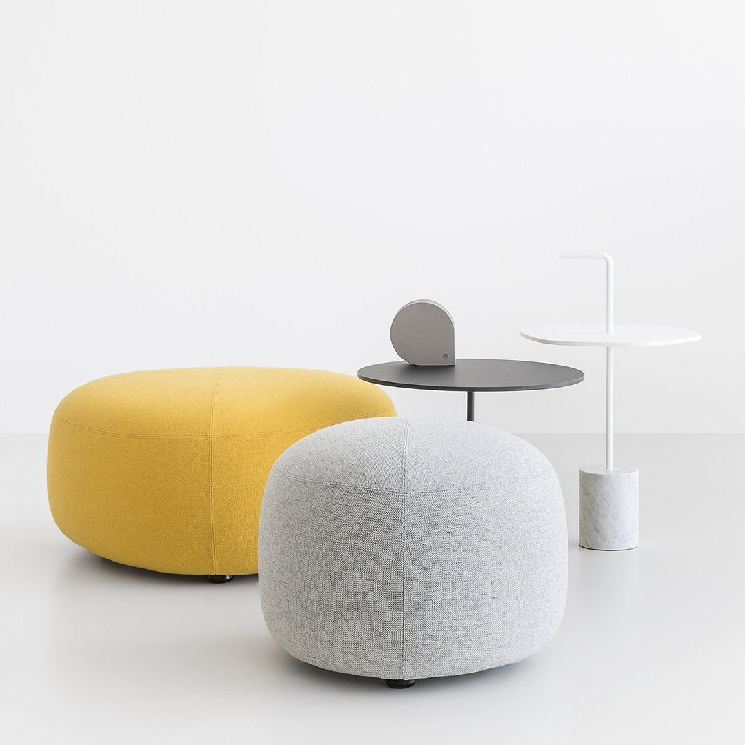 Yellow and gray upholstered poufs with a minimalist black and white side table, all against a light grey background.