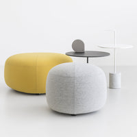 Yellow and grey poufs with smooth, rounded shapes, paired with a minimalist black and white side table.
