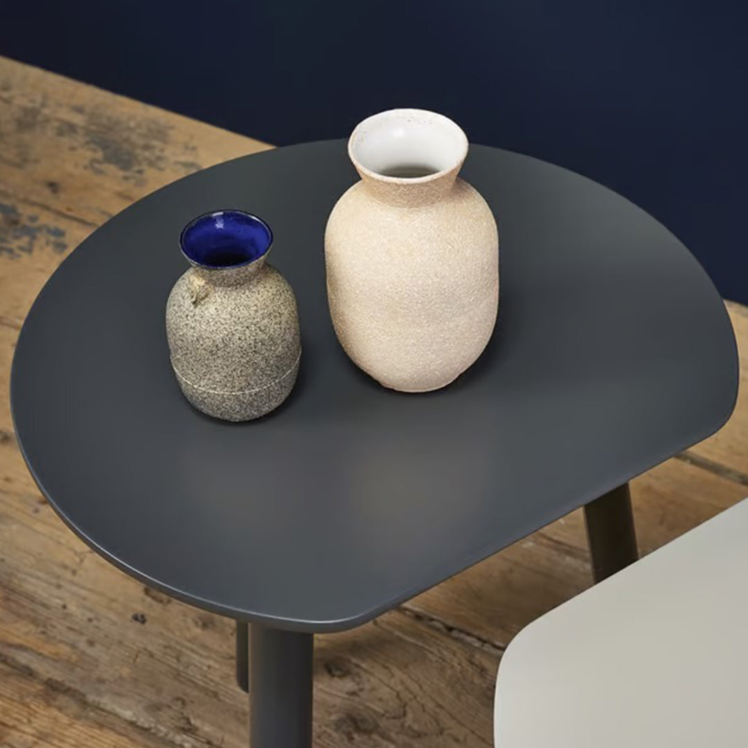 Two textured vases in cream and gray on a round gray table against a dark blue wall, featuring subtle modern patterns.
