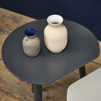 Two textured vases in cream and gray on a round gray table against a dark blue wall, featuring subtle modern patterns.
