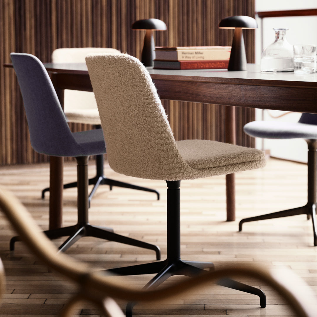 Three stylish dining chairs in beige, lavender, and light gray upholstery at a modern wooden table.