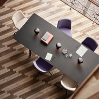 "Modern black dining table with purple and cream chairs on a wooden patterned floor."