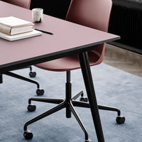 Stylish burgundy chair with black legs, paired with a sleek black table on a soft blue rug. Modern office decor.