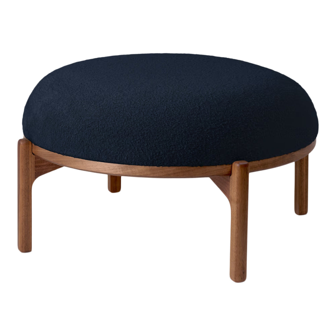Round navy ottoman with a textured fabric top and natural wood legs, perfect for modern decor.