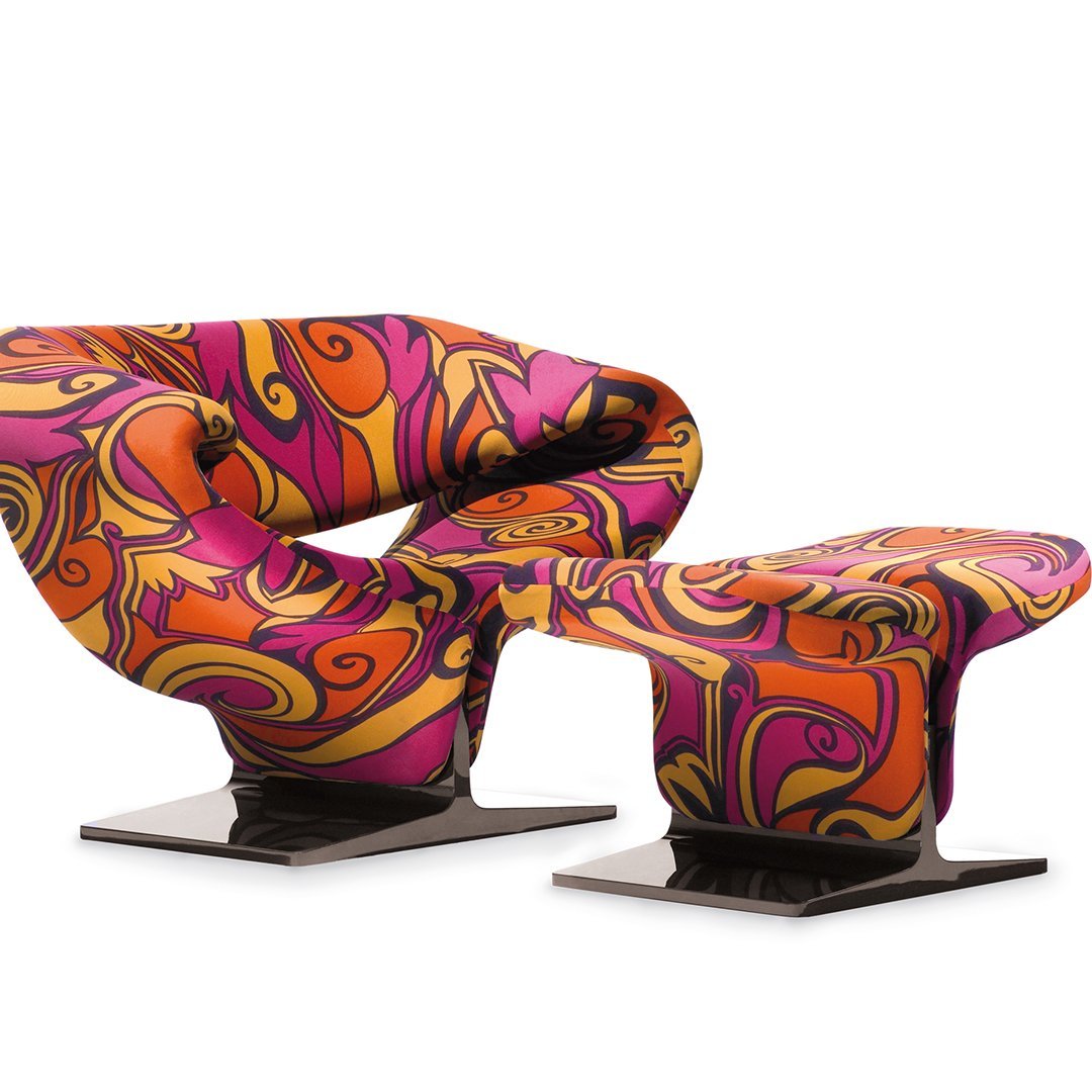 Colorful mid-century modern chair and ottoman in vibrant pink, orange, and swirls pattern on sleek black bases.