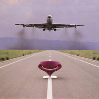 "Vibrant purple and red patterned chair against a dramatic sky backdrop and open runway."