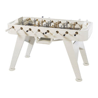 White foosball table with gold and silver players, featuring a sleek modern design and contrasting black handles.