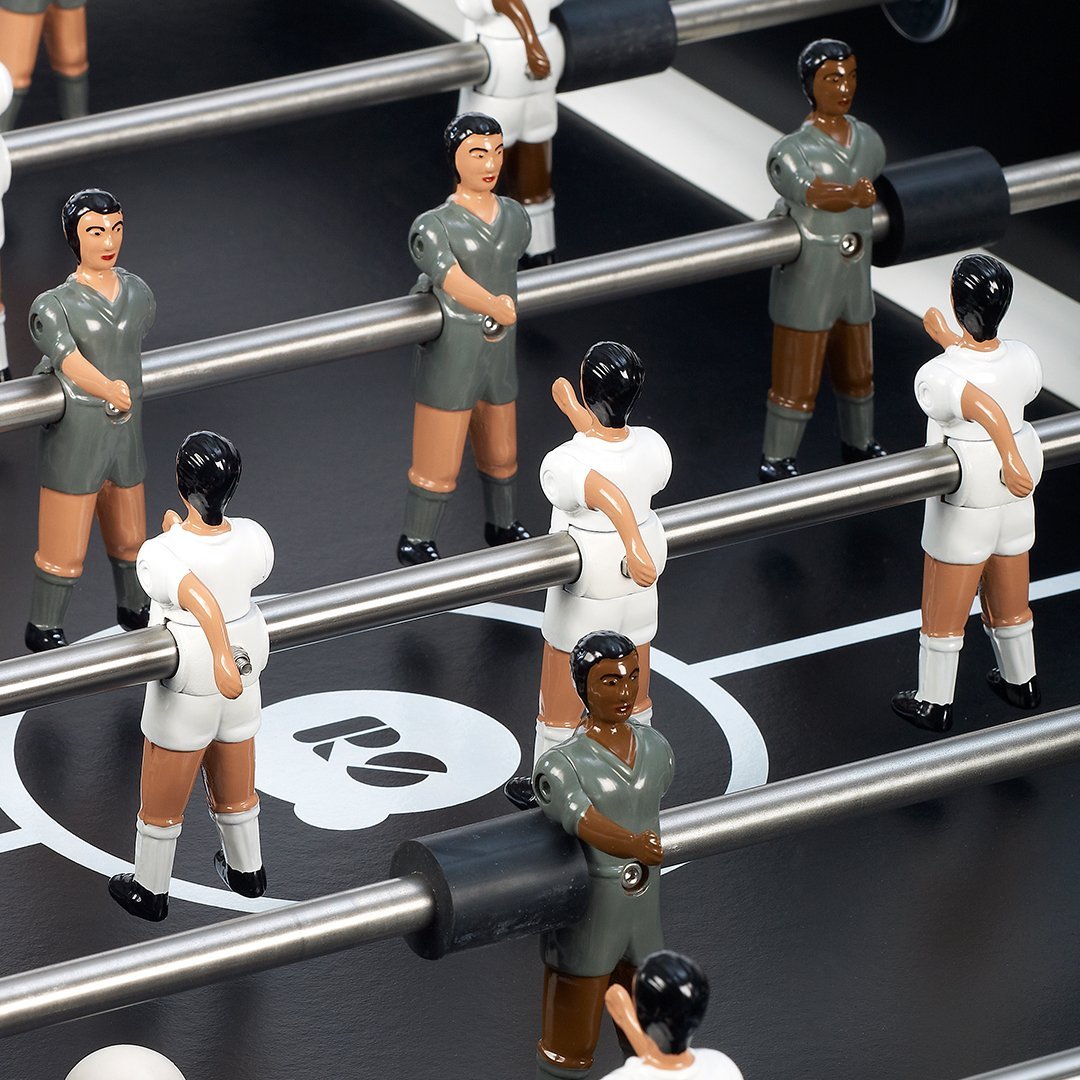 Foosball table players in gray, white, and brown with black and white accents, set against a dark background.