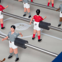 "Colorful foosball players in red and gray uniforms on a light gray tabletop with white markings."