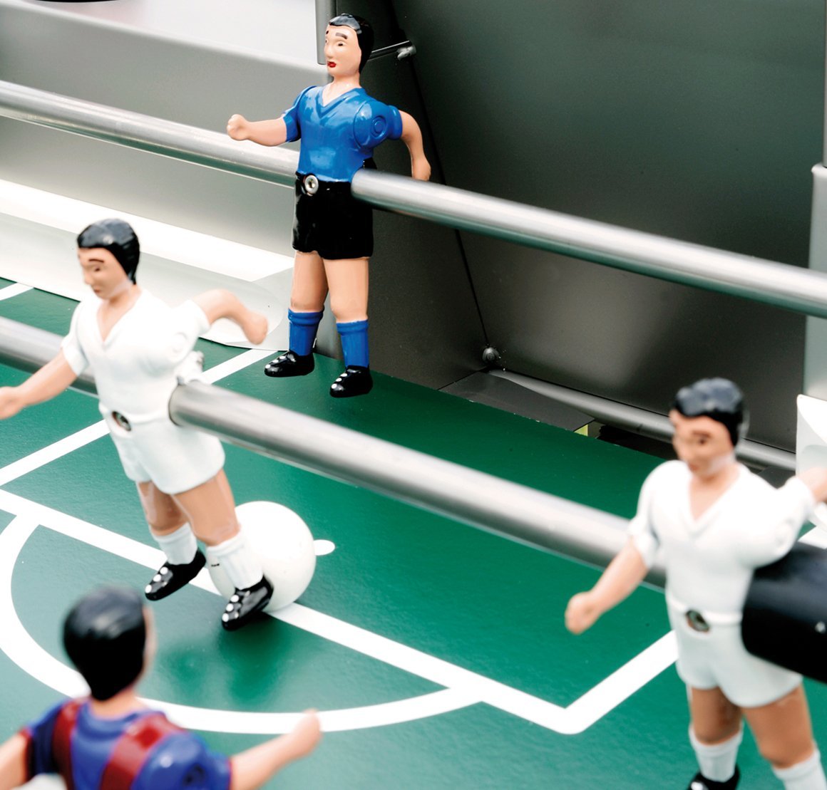 Colorful foosball figures in blue and white on a vibrant green playing field with white court markings.