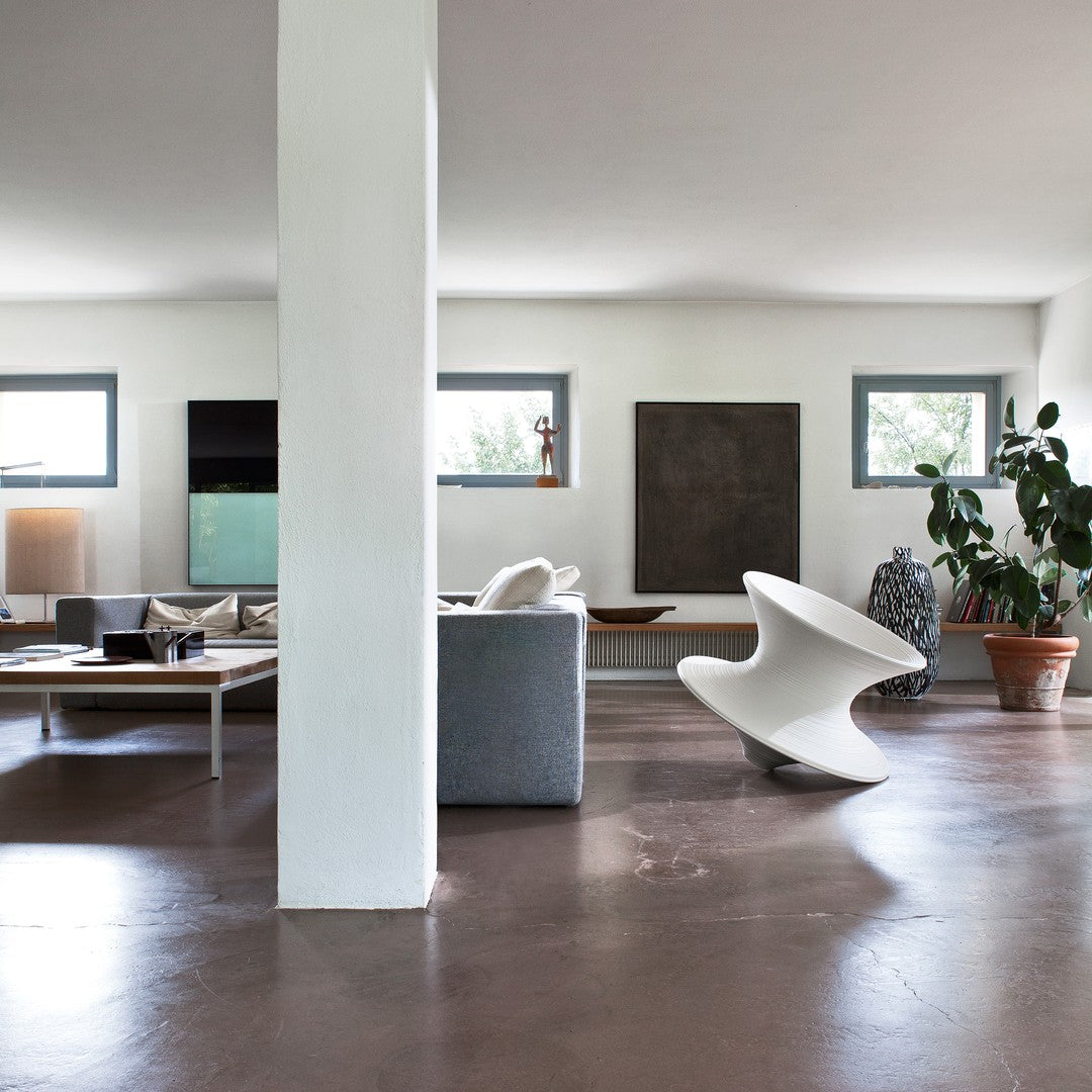 Modern living room with gray furniture, white columns, earthy brown floors, and lush green plants for a stylish look.