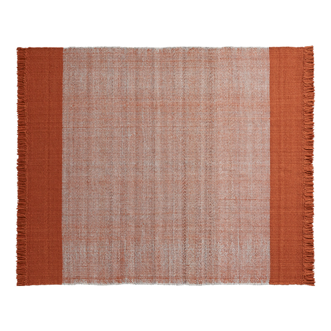 Textured fabric placemat in soft pink with rust-orange borders and fringed edges. Ideal for stylish table settings.