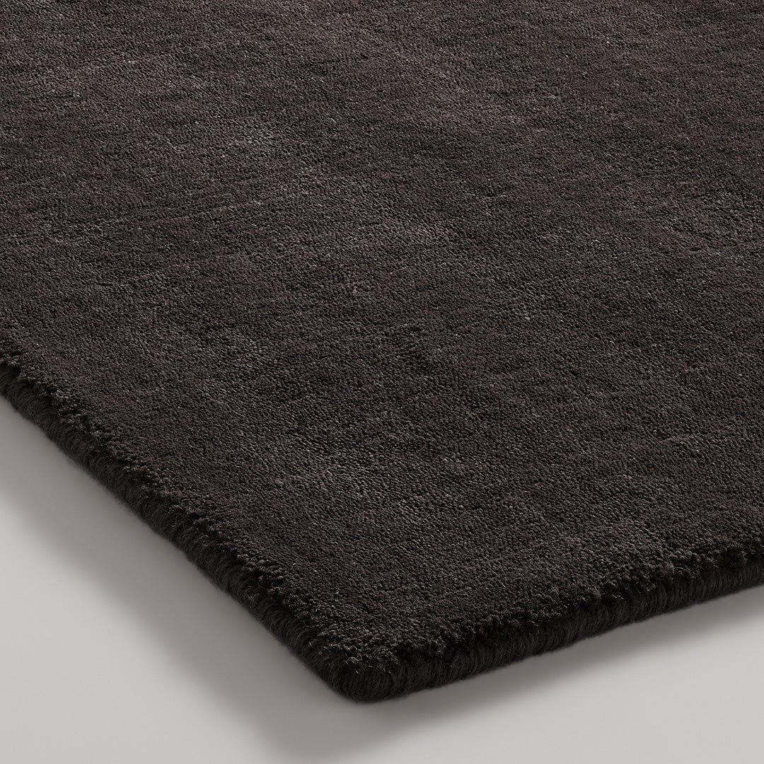 Black plush rug with a soft texture and subtle sheen, perfect for modern decor.