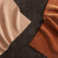 "Soft beige and deep rust fabric swatches on a dark textured background."