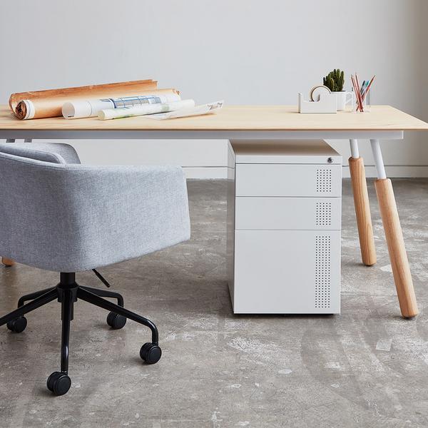 Modern gray office chair beside a light wood desk with a sleek white drawer unit; minimalistic design with neutral tones.