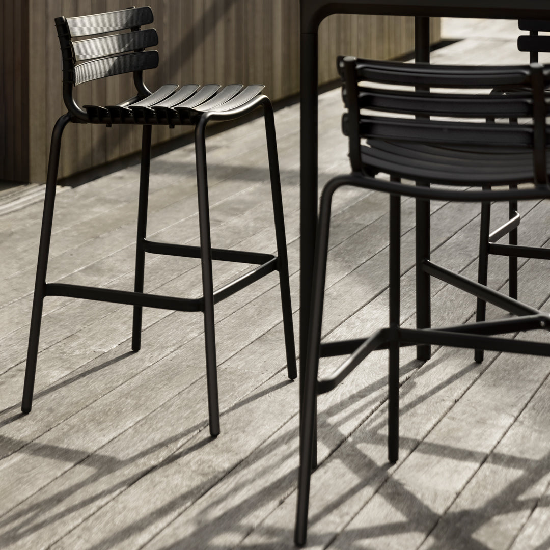 Black metal bar stools with slatted design, featuring sleek lines and a modern aesthetic. Perfect for outdoor settings.