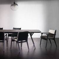 Modern black dining table with sleek lines, complemented by contrasting light gray and black dining chairs.