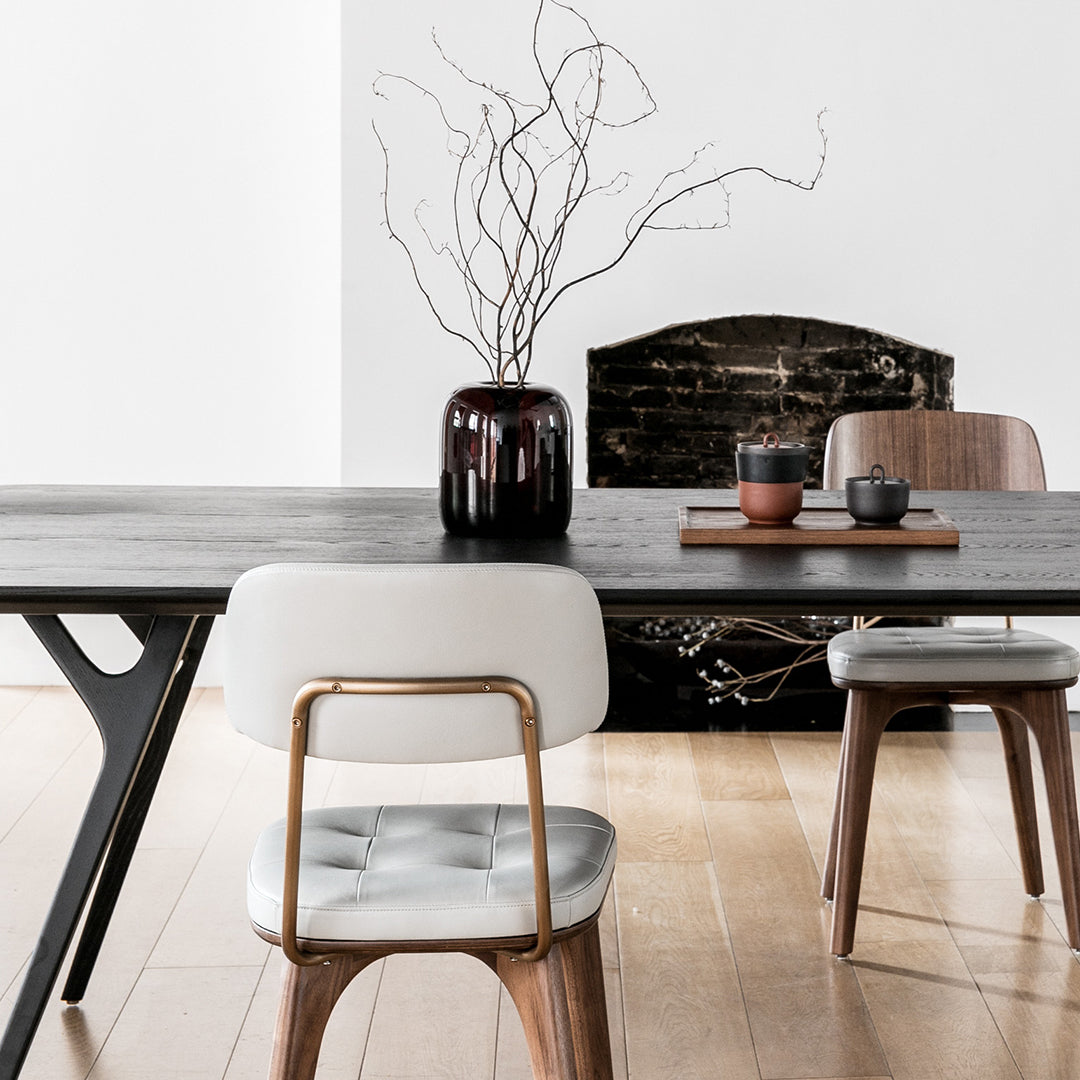 "Modern black wooden dining table with sleek white and brown chairs, featuring minimalist patterns and a neutral backdrop."