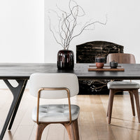 "Modern black wooden dining table with sleek white and brown chairs, featuring minimalist patterns and a neutral backdrop."