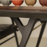 Dark wood table with a sleek design, topped with colorful ceramic pots in shades of orange, beige, and gray.