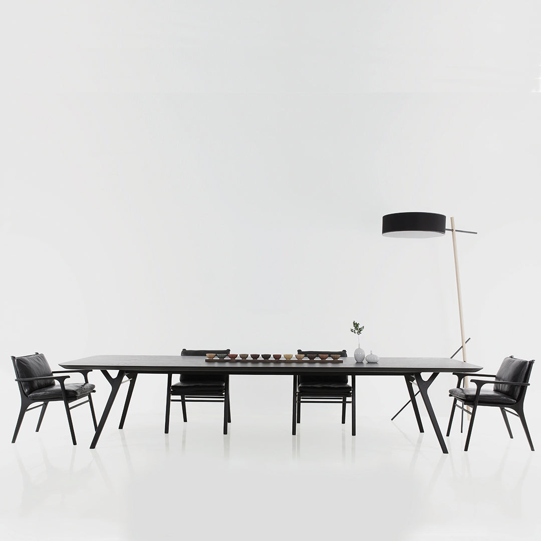 Sleek black dining table with modern geometric patterns, paired with stylish black chairs.