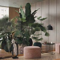 "Soft pink ottomans, lush green plants, geometric black table, and warm wooden flooring create a cozy, modern living space."