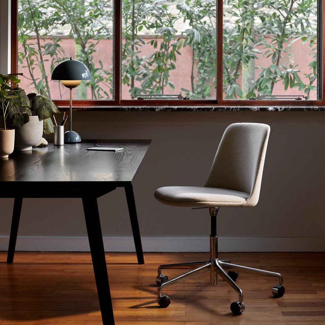 Cream and gray office chair with sleek fabric, set against a warm wooden floor and natural greenery backdrop.