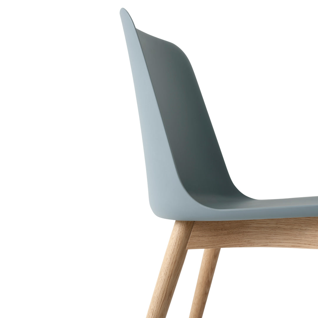 Light blue modern chair with smooth curves and natural wood legs, blending minimalist design with contemporary colors.