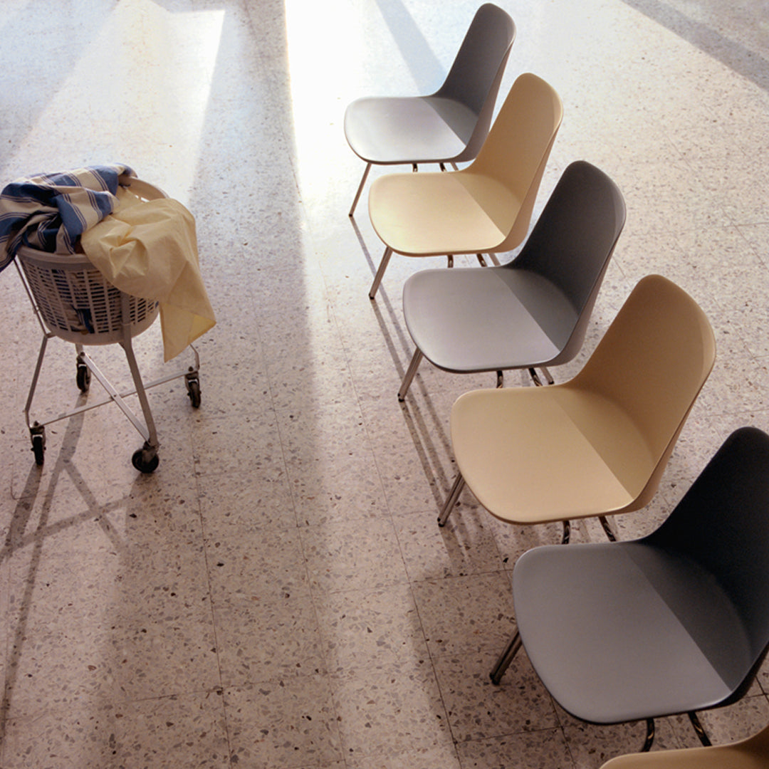 "Modern chairs in soft gray, beige, and pastel tones with smooth, minimalist design on textured floor."
