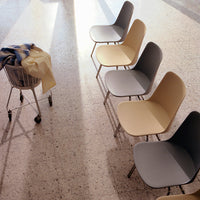 "Modern chairs in soft gray, beige, and pastel tones with smooth, minimalist design on textured floor."