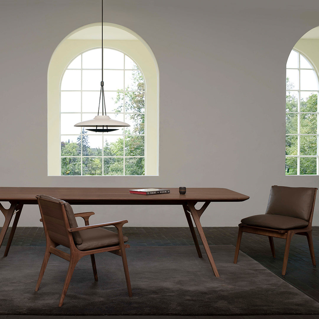 Modern wooden dining table in rich brown with sleek chairs, set against a neutral backdrop and light gray rug.