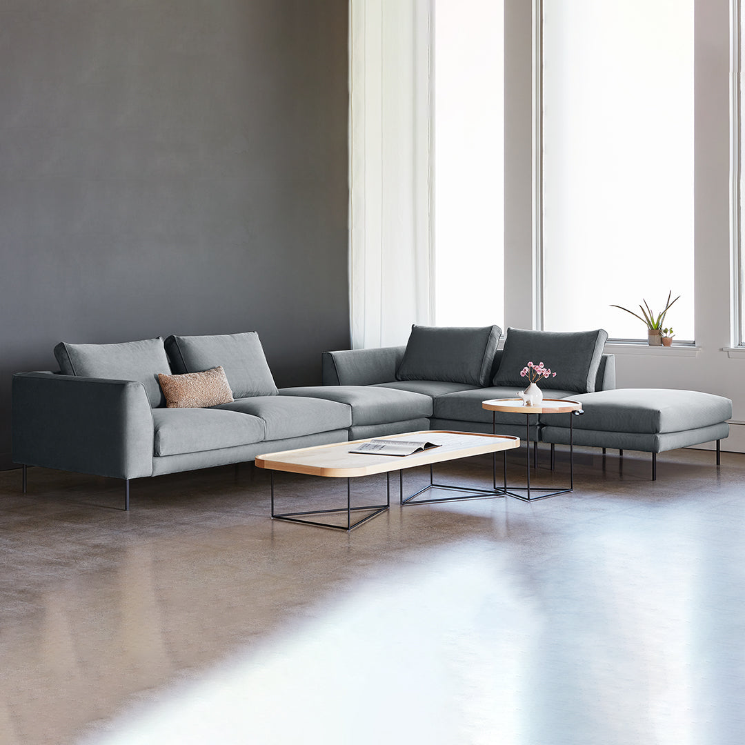 Modern gray sectional sofa with clean lines, complemented by a minimalist coffee table in a light wood finish.