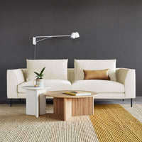 Beige sofa with a gold accent pillow, paired with a light wood coffee table on a striped beige and yellow rug.