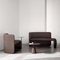 Modern brown sofa set in a minimalist room with soft, curved shapes and a sleek, neutral backdrop.
