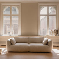 Beige textured sofa with soft rounded shapes, complementing light-toned room decor and natural light.