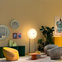 Vibrant yellow and soft gray armchairs with round mirrors, green plant, and colorful patterned decor against a warm background.