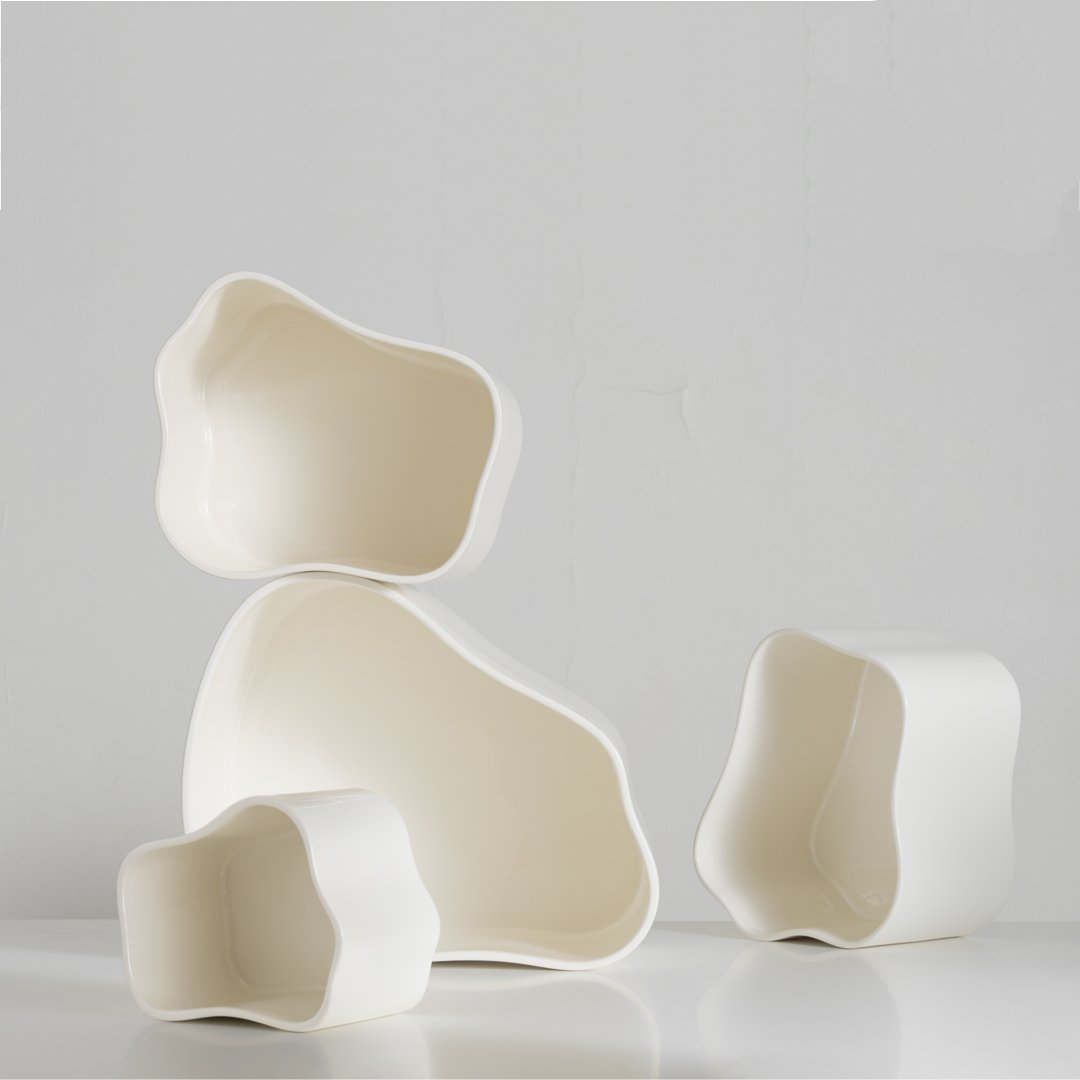 Set of four organic-shaped white ceramic bowls with smooth, glossy finishes and unique wavy edges.