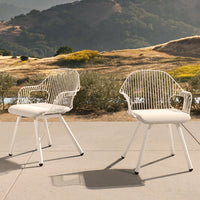 White wire chairs with a sleek design and soft white cushions, set against a natural landscape backdrop.