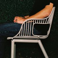 Modern beige chair with sleek lines and a unique cut-out design, set against a dark, textured background.
