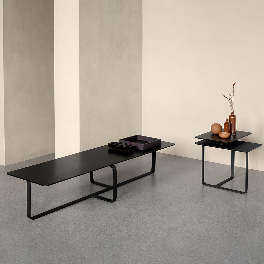 Black minimalist coffee tables with sleek metal frames, set against a soft, neutral background.