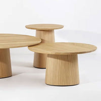 Natural light wood coffee tables with smooth round tops and tapered bases, showcasing a minimalist design.