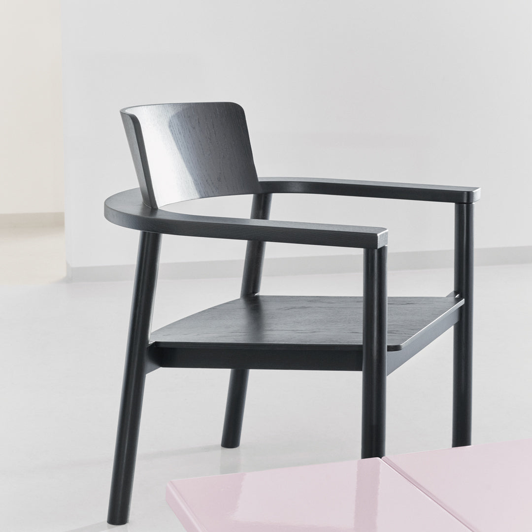 Black wooden armchair with a minimalist design and smooth, clean lines against a light background.