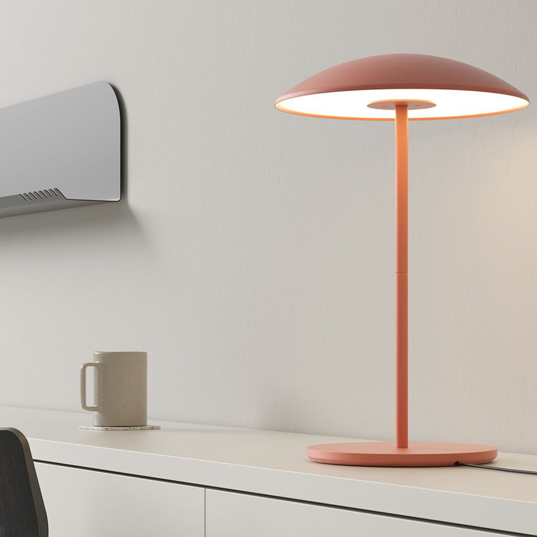 Modern pink table lamp with a sleek round shade and minimalistic design, set against a neutral backdrop.