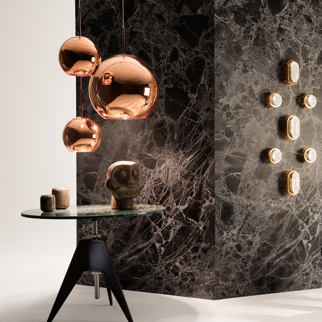 Copper hanging lights against a dark marble wall; geometric patterns and sleek, modern design elements.