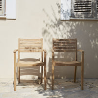 Natural wood chairs with slatted design against a light-colored wall, featuring a warm, earthy tone.